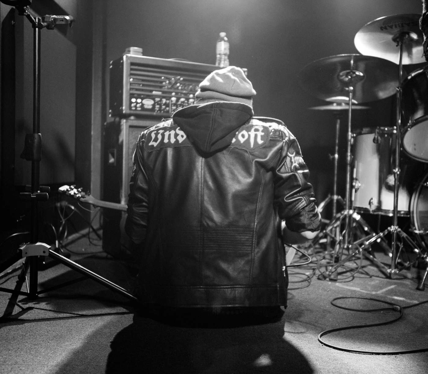 Photograph of Undercroft black metal band guitarist on stage. Jacket has Undercroft backpatch.